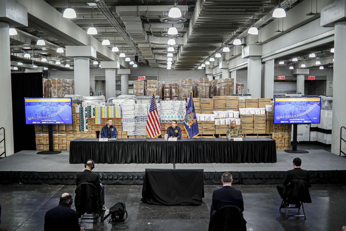 In this March 24, 2020 photo, New York Gov. Andrew Cuomo, center, speaks while practicing social distancing, during a news conference at the Jacob Javits Center, in New York. Cuomo has lately shied away from coming face to face with reporters as he faces sexual harassment allegations. The Democratic governor gained national attention last spring for televised news briefings at which he answered barrages of questions from journalists.  (John Minchillo)