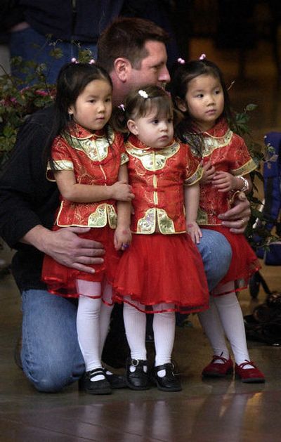 
Mark Lucas listens to Dragon Wind Music with his daughters, from left, Vanessa Lucas, 4, Zoe Lucas, 2, and Valerie Lucas, 4, at River Park Square in Spokane on Sunday at the Chinese New Year celebration. 
 (Liz Kishimoto / The Spokesman-Review)
