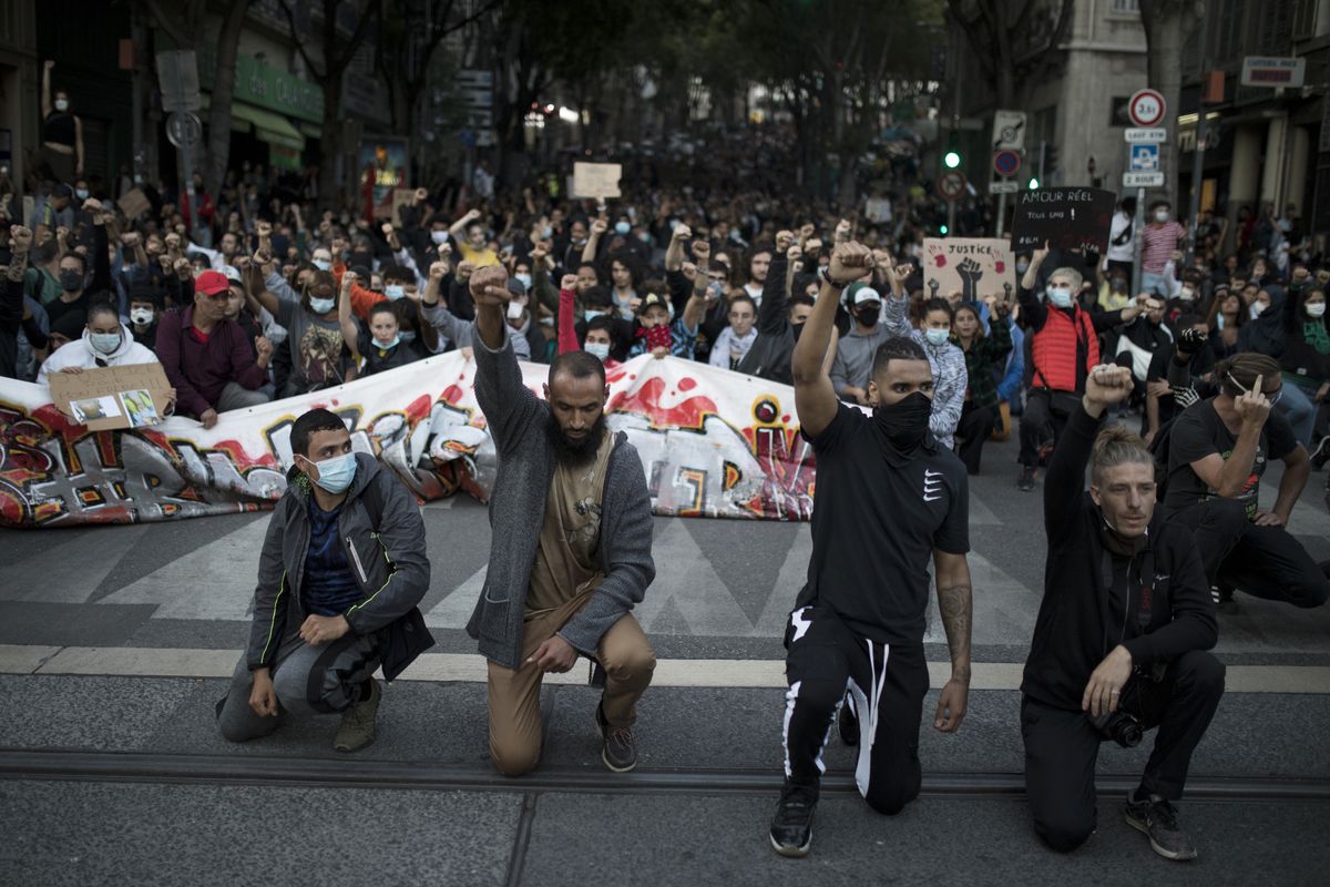 Protesters raise their fists and kneel in front of French riot police during a march against police brutality and racism in Marseille, France, Saturday, June 13, 2020, organized by supporters of Adama Traore, who died in police custody in 2016. Several demonstrations went ahead Saturday inspired by the Black Lives Matter movement in the U.S.  (Daniel Cole)