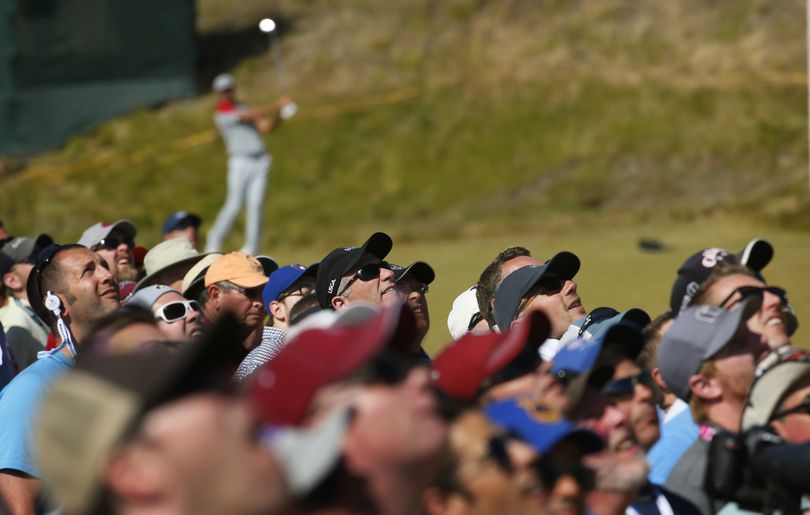 Fans watch as Dustin Johnson hits his tee shot on the ninth hole during the third round of the U.S. Open golf tournament at Chambers Bay on Saturday. (AP)