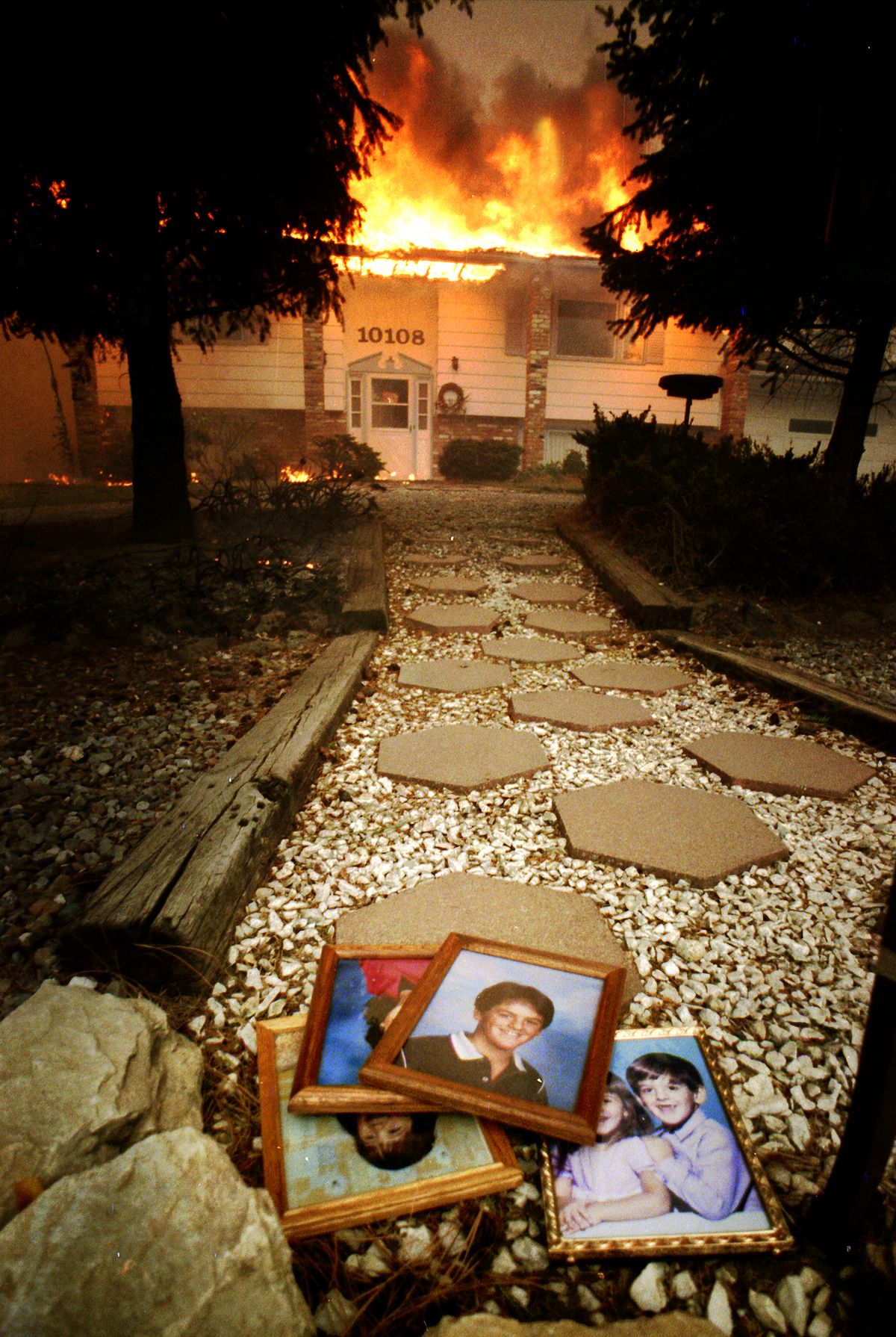 A firefighter salvaged family photos from a Ponderosa home  and laid them at the end of the walkway. (Colin Mulvany / The Spokesman-Review)