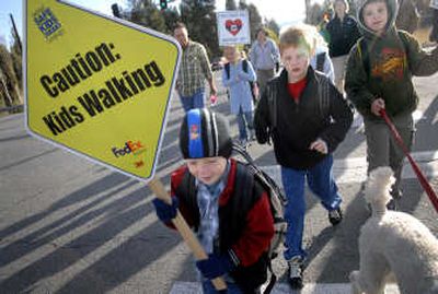 
Chester Elementary first-grader Joel Thompson, left, leads a group of parents, teachers and students, including third-graders Tyler Haase, center, and Ethan Jones, right, across Highway 27 on their way to school on International Walk to School Day in Spokane Valley on Wednesday.
 (Holly Pickett / The Spokesman-Review)
