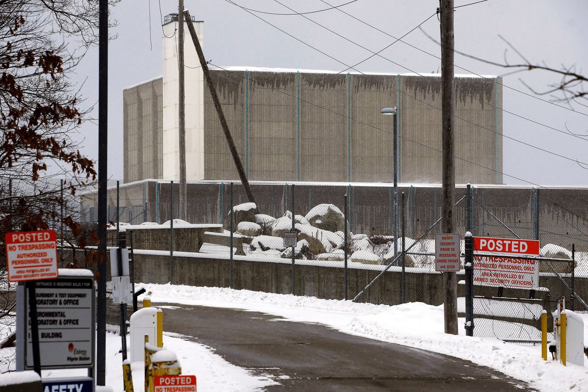 FILE - A no trespassing sign is posted near the entrance to the Pilgrim Nuclear Power Station, at rear, Thursday, Feb. 28, 2019, in Plymouth, Mass. One million gallons of radioactive water is contained inside the former nuclear power plant along Cape Cod Bay. The plant's owner, Holtec International, is considering treating the water and discharging it into the bay. Local residents, shell fishermen and politicians disapprove of the plan.  (Steven Senne)