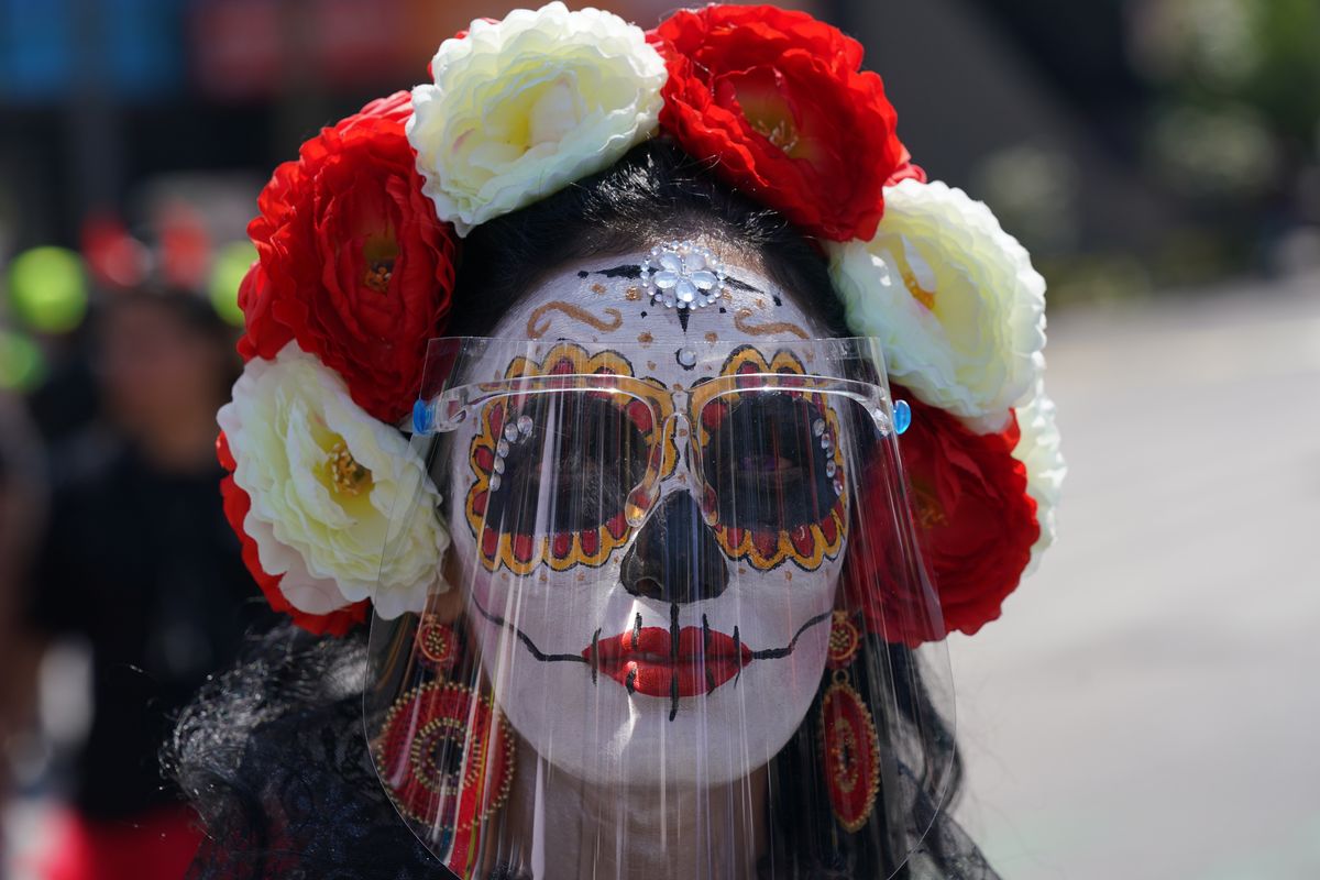 A woman made up as a “Catrina” and wearing a face shield posed for a photo during Day of the Dead festivities in Mexico City on Sunday. Altars and artwork from around the country were on display in a parade as Mexicans honor the Day of the Dead.  (Fernando Llano)