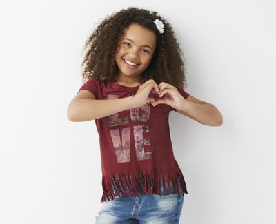 This photo provided by J.C. Penney shows a model wearing an Arizona short-sleeve, faux suede, fringe top and jeans as part of the store’s back-to-school offerings. There are plenty of fashion trends that experts say should help pique shoppers’ interest for the back-to-school season. (Steve Visneau / Associated Press)