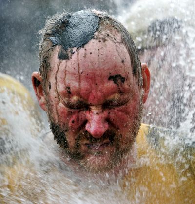 ORG XMIT: XBBL109 A man gets a shower after he played soccer in the mud flats at Brunsbuettel near to the North Sea, northern Germany, during the annual mud flats festival on Sunday, Aug. 30, 2009. (AP Photo/Heribert Proepper) (Heribert Proepper / The Spokesman-Review)