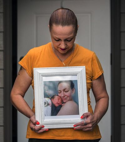 Kjersty Rusch of Marysville holds a photo of daughter Autumn Stone cradling her 1-day-old son. Of Autumn’s death, she says “There’s so much I just don’t understand.”  (Steve Ringman/Seattle Times)