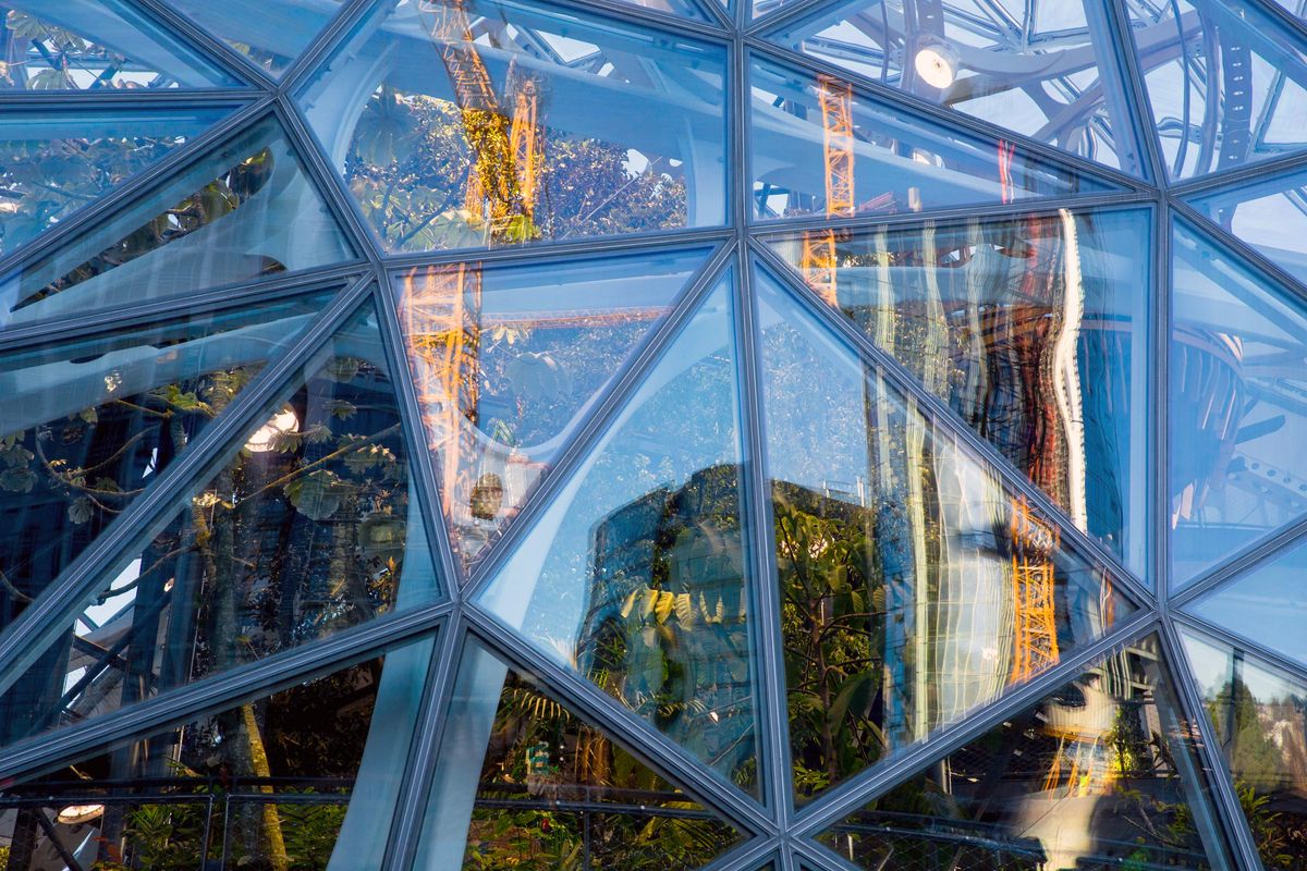 Cranes reflect in the Amazon Spheres while creating new buildings in downtown Seattle. (Courtney Pedroza/The Seattle Times)
