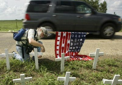 
Roger Cuthbertson of Shorewood, Minn., helps repair some of the crosses damaged when a pickup drove through the makeshift memorial near President Bush's ranch. 
 (Associated Press / The Spokesman-Review)