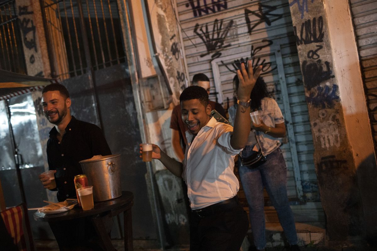 A man dances during a street performance by the Brazilian band Atitude Nossa as the restrictions related to the COVID-19 pandemic are eased in Rio de Janeiro, Brazil, Monday, Oct. 5, 2020. Since the beginning of October, live shows are now permitted in Rio de Janeiro.  (Silvia Izquierdo)