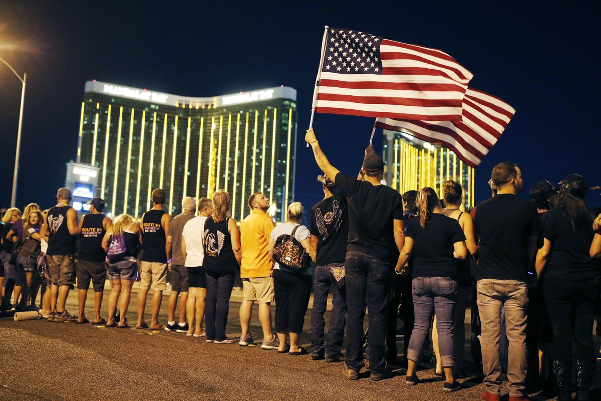 In this Oct. 1, 2018 photo, people form a human chain around the shuttered site of a country music festival where a gunman opened fire on the first anniversary of the mass shooting in Las Vegas. A panel planning a permanent memorial at the Las Vegas site of the deadliest mass shooting in modern American history is focusing on stories about the more than 58 people killed by gunfire and thousands left wounded and emotionally scarred, and on lessons learned. The 1 October Memorial Committee told Clark County lawmakers on Wednesday, Aug. 25, 2021, that focus groups indicated the project should avoid political topics and personal details about the shooter.  (John Locher)