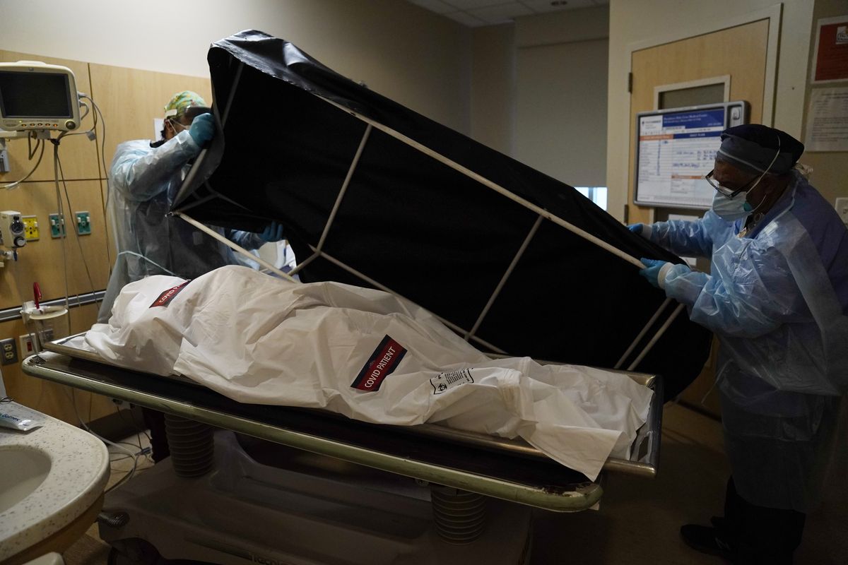 FILE - In this Jan. 9, 2021 file photo, transporters Miguel Lopez, right, Noe Meza prepare to move a body of a COVID-19 victim to a morgue at Providence Holy Cross Medical Center in the Mission Hills section of Los Angeles. The U.S. death toll from COVID-19 has topped 600,000, even as the vaccination drive has drastically slashed daily cases and deaths and allowed the country to emerge from the gloom.  (Jae C. Hong)