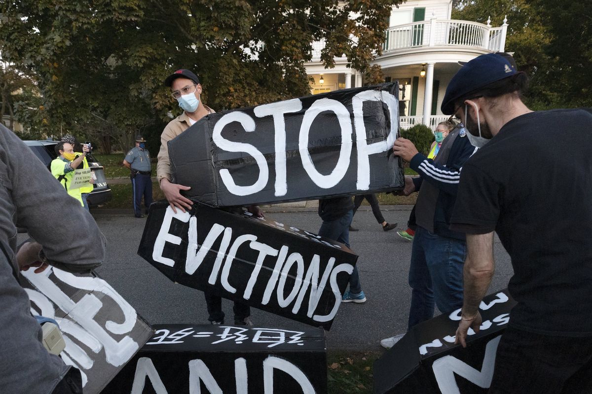In this Oct. 14, 2020 photo, housing activists erect a sign in front of Massachusetts Gov. Charlie Baker
