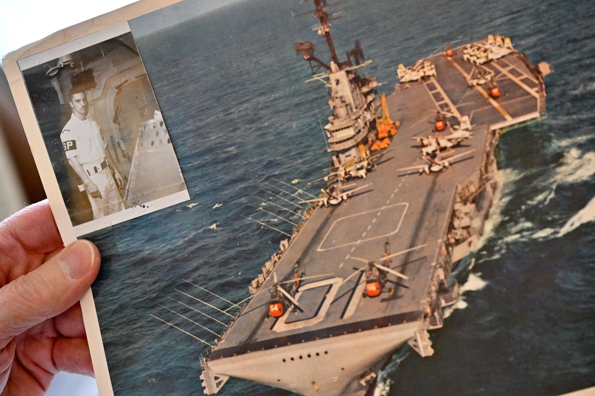 Michael Driscoll, an atomic veteran shows a historic photo of himself and an image of his ship the USS Yorktown on Saturday, April 29, 2023, at his home in Spokane, Wash.  (Tyler Tjomsland/The Spokesman-Review)