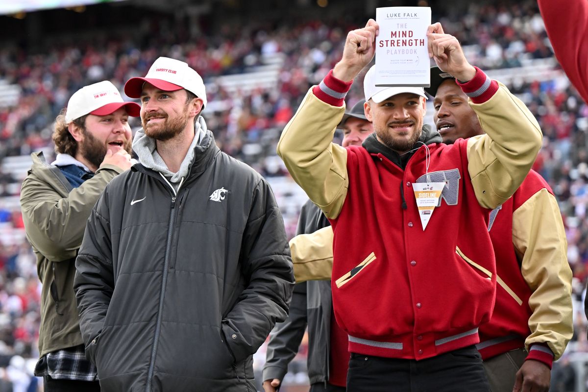 Former WSU quarterback Luke Falk, left, smiles as former teammate, linebacker Isaac Dotson holds up Falk’s book, “The Mind Strength Playbook: Master Your Mind. Elevate Your Game,” during a timeout Saturday on Gesa Field at Martin Stadium in Pullman.  (Tyler Tjomsland/The Spokesman-Review)