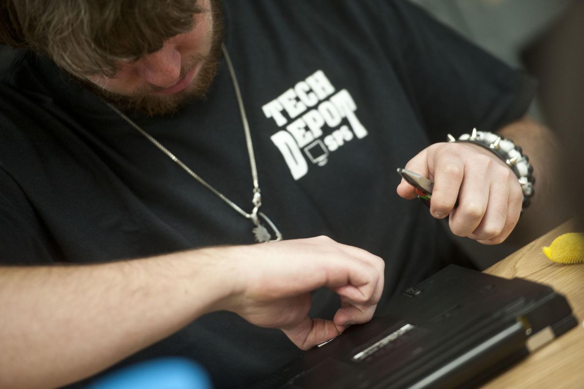 Joey Tilley cleans a laptop at Instructional Tech Support in Spokane Valley on Friday, Dec. 7, 2018. Spokane Public Schools has a program in which used laptops are refurbished and donated to Spokane Public Libraries for students to check out. (Kathy Plonka / The Spokesman-Review)