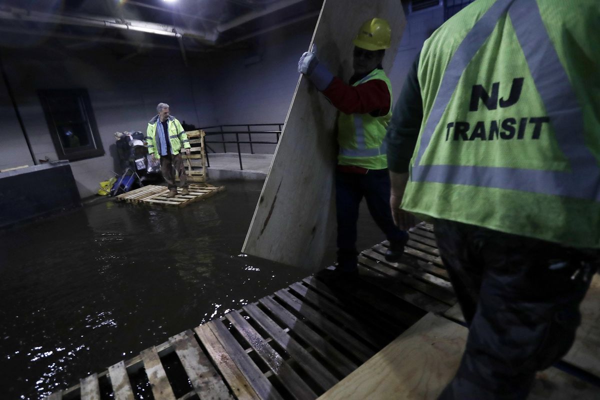 New Jersey Transit workers lay down pallets and boards for commuters to walk on a flooded hallway adjacent to the site of a train crash at the Hoboken Terminal, Friday, Sept. 30, 2016, in Hoboken, N.J. Commuters are using alternative travel in and out of Hoboken a day after a commuter train crashed into the rail station, killing one person and injuring more than 100 people. (Julio Cortez / Associated Press)