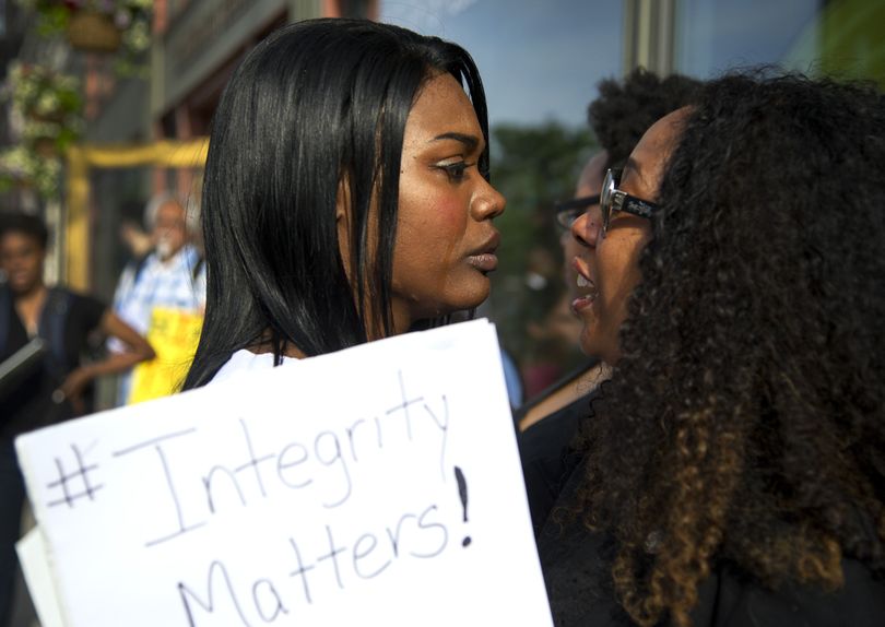 Demonstration organizer and NAACP member Kitara Johnson, left, receives support from friend Angela Jones before speaking to a crowd gathered outside the local NAACP office in downtown Spokane on Monday. (Colin Mulvany)