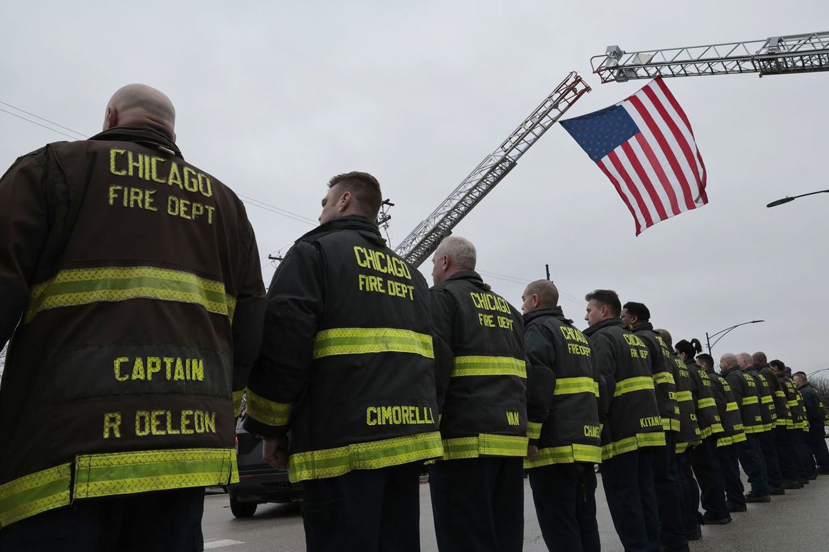 Firefighters stand at attention for a procession carrying the body of a fallen Chicago firefighter at the Cook County medical examiner