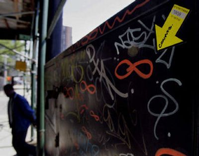 
A pedestrian passes a Yellow Arrow sign in New York. Yellow Arrow encourages people to plaster adhesive arrows with unique codes to physical landmarks or even other people allowing people to use text messaging to get information about the place or person. 
 (Associated Press / The Spokesman-Review)