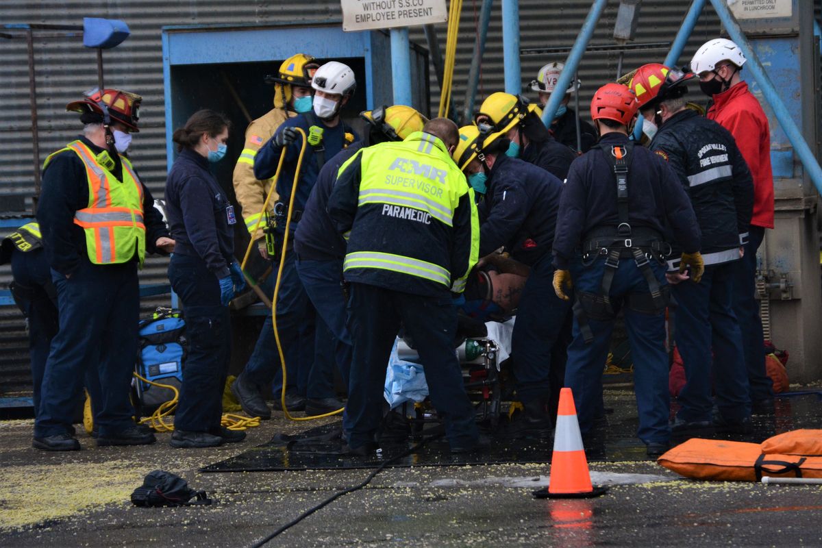 Emergency crews extricate a man from a grain elevator Monday at Spokane Seed Company in Spokane Valley.  (Greg Mason / The Spokesman-Review)