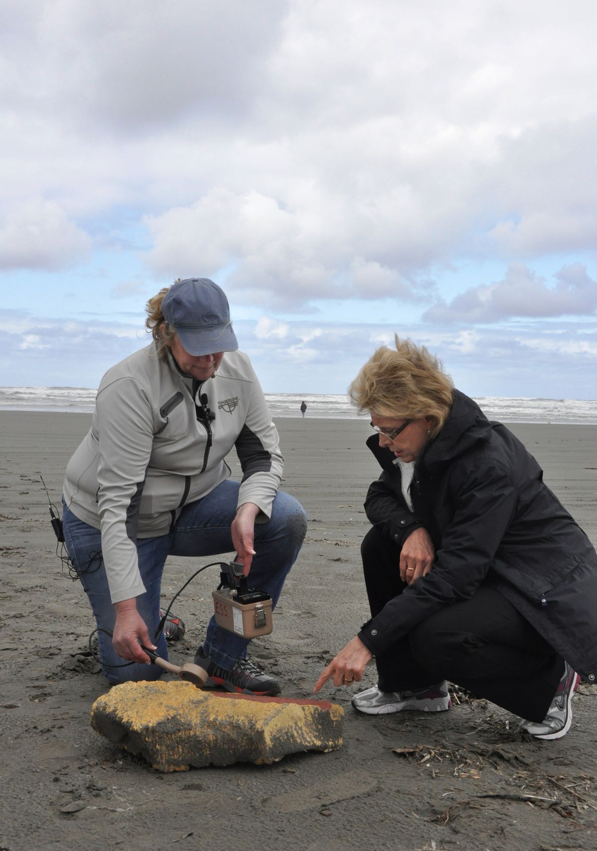 Lynn Albin, a radiation expert from the state Department of Health, explains to Gov. Chris Gregoire, right, how state workers check some suspected tsunami debris by running a Geiger counter Monday morning over a piece of Styrofoam that washed up on the beach. (Jim Camden)