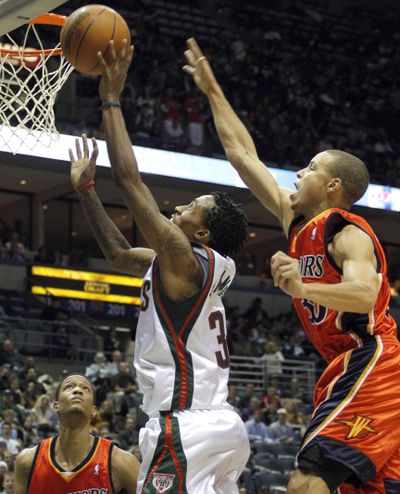 Milwaukee Bucks’ Brandon Jennings, center, drives against Golden State’s Stephen Curry, right, and Anthony Randolph. (Associated Press)