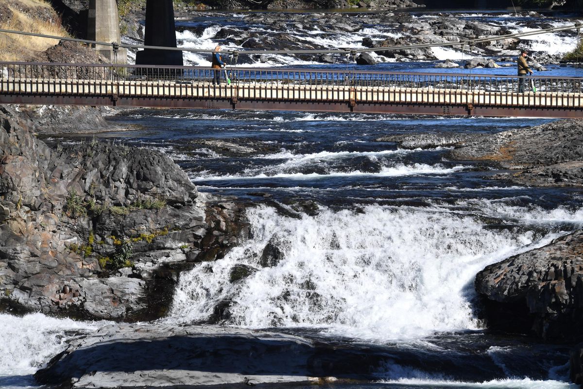 Riders on Lime scooters cross the footbridge over the Spokane River Upper Falls. (Dan Pelle / The Spokesman-Review)