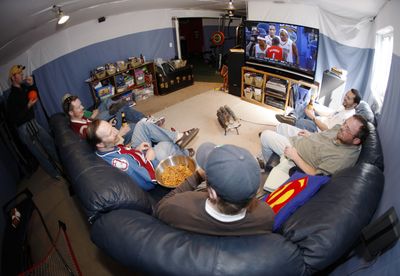 From right, Greg Nuccio, John Otterson, Tom Bruce, Joe Stone, Eirik Thune-Larsen and Fred Wilson sit on a pair of couches to watch college basketball conference finals on a big-screen television while Bill Reeves, back left, looks on in Stone’s basement turned into a man cave in Thornton, Colo., last week.  (Associated Press / The Spokesman-Review)