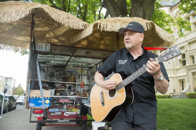Doug Bickford, who runs the hotdog stand in front of the Spokane County Courthouse, plays an original blues number about being the hotdog man Friday, May 19, 2017. The hot dog stand is the meeting place for lawyers, secretaries, offenders and commissioners each day Bickford is open. (Jesse Tinsley / The Spokesman-Review)