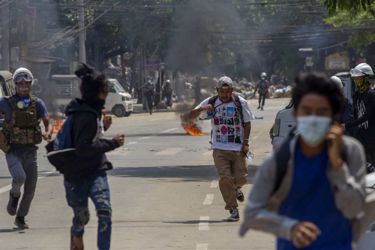 Anti-coup protesters abandon their makeshift barricade and run as armed riot policemen charge in Yangon, Myanmar Tuesday, March 16, 2021. Demonstrators in several areas of Myanmar protesting last month’s seizure of power by the military held small, peaceful marches before dawn Tuesday, avoiding confrontations with security forces who have shot dead scores of their countrymen in the past few days.  (STR)