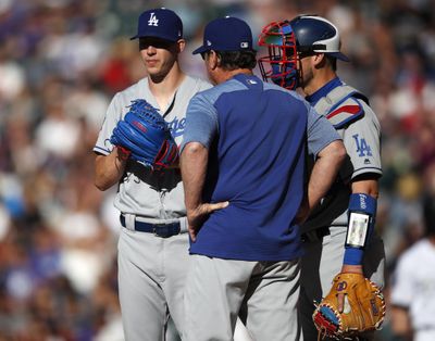 Los Angeles Dodgers starting pitcher Walker Buehler, left, confers with pitching coach Rick Honeycutt and catcher Yasmani Grandal after Buehler gave up an RBI single to Colorado Rockies' Charlie Blackmon during the second inning of a baseball game Saturday, June 2, 2018, in Denver. (David Zalubowski / AP)