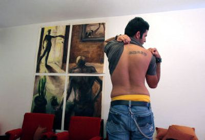 
Twenty-year-old Yasha shows his back tattooed with the English letters KMKKY representing the names of members of his family in Tehran, Iran, on  July 21. 
 (Associated Press / The Spokesman-Review)