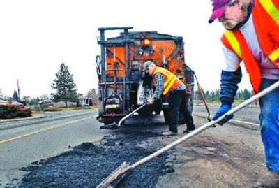 
Bob Loveless, right, and Dennis Thompson of the transportation department, fill in potholes Wednesday on Northwest Boulevard.
 (Photos by Jed Conklin / The Spokesman-Review)