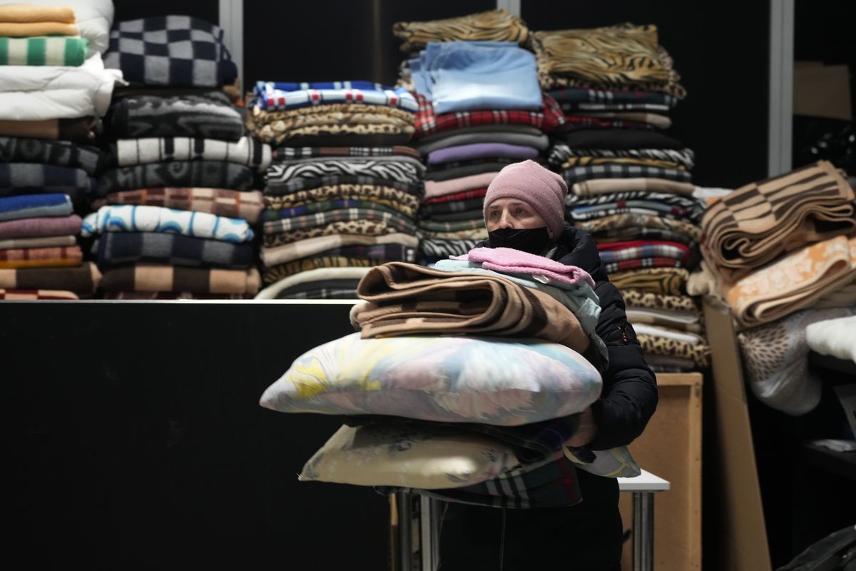 A Ukrainian refugee carries pillows and blankets at a refugee center in Nadarzyn, near Warsaw, Poland, Thursday, March 31, 2022. The talks between Ukraine and Russia will resume on Friday as NATO Secretary-General says Russia does not appear to be scaling back its military operations in Ukraine but is instead redeploying forces to the eastern Donbas region.  (Czarek Sokolowski)