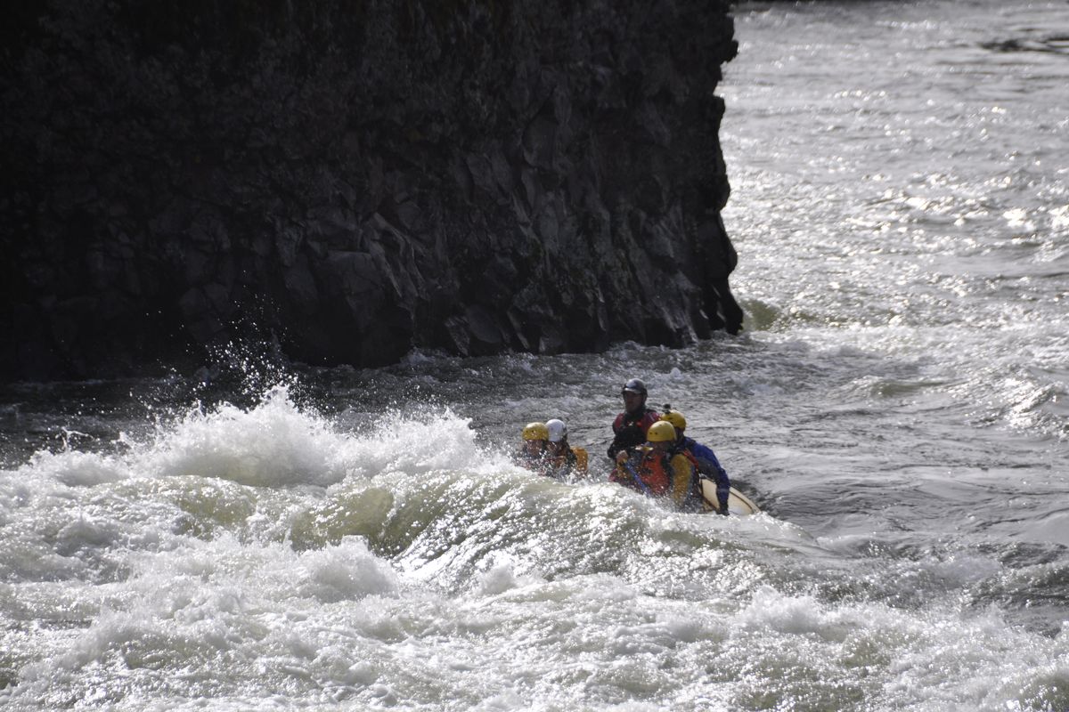 A raft of Peak 7 Adventures paddlers busts through the first big rapid entering the Bowl and Pitcher Area above the Riverside State Park suspension bridge with river flows around 16,000 cfs on March 13, 2016. In following photos, one of the rafters is ejected and rescued. (Rich Landers)