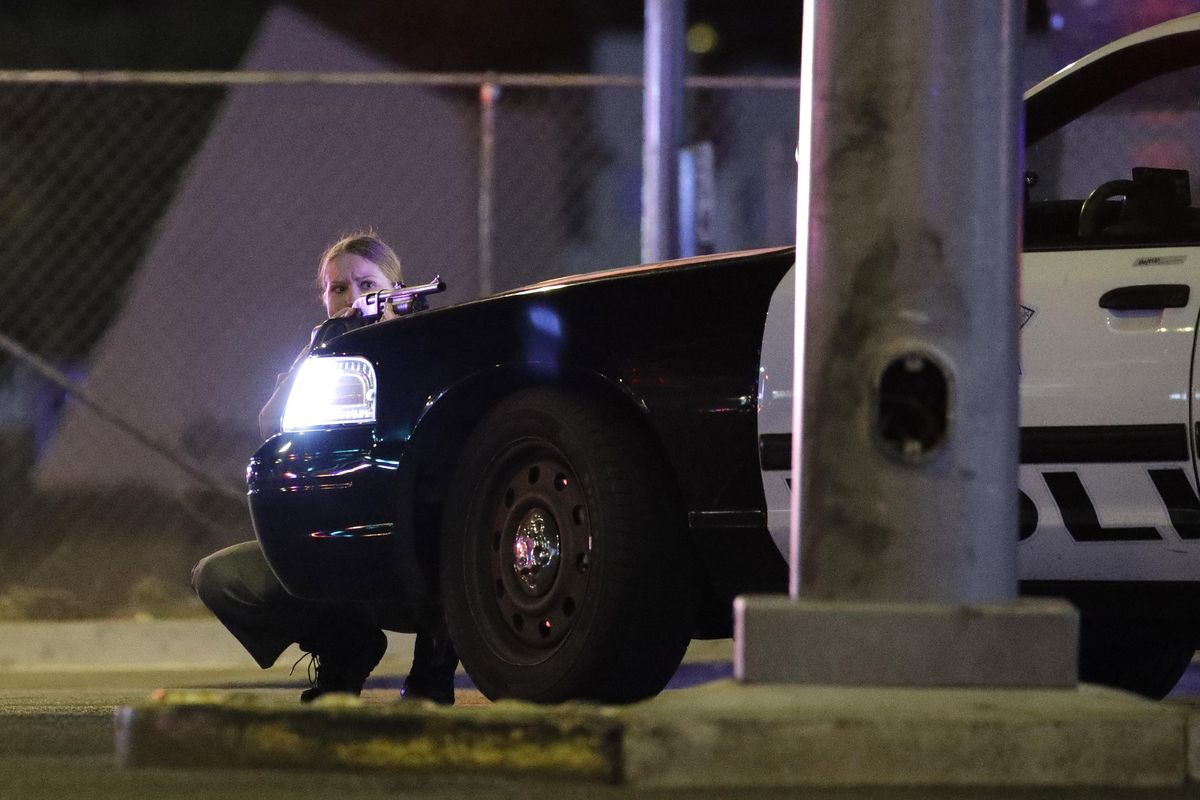 A police officer takes cover behind a police vehicle during a shooting near the Mandalay Bay resort and casino on the Las Vegas Strip, Sunday, Oct. 1, 2017, in Las Vegas. (John Locher / Associated Press)