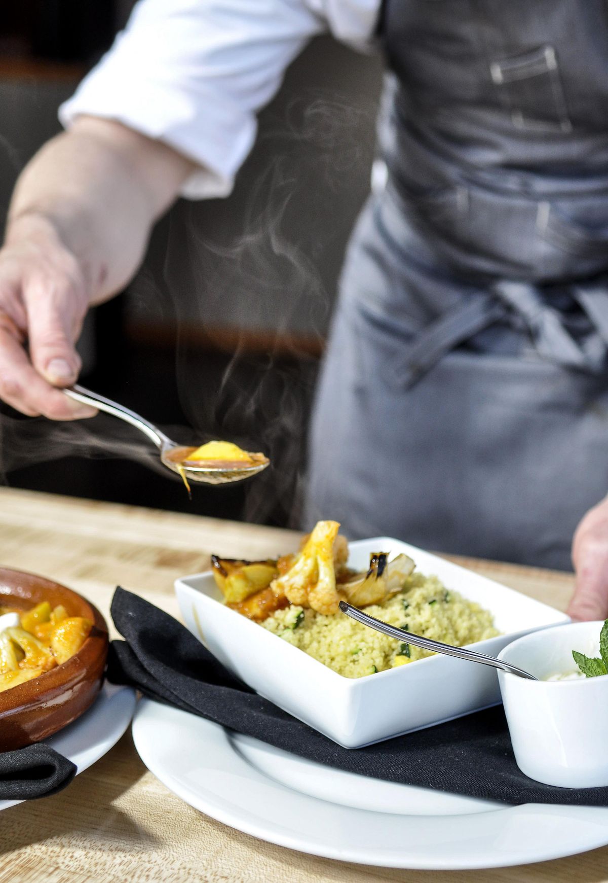 Chef Philip Stanton spoons his Seven Vegetable Tagine atop couscous at his new Park Lodge restaurant, which opens Friday, April 27, 2018, in Spokane’s Kendall Yards. (Adriana Janovich / The Spokesman-Review)