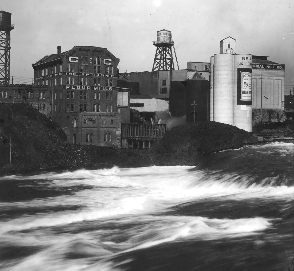 Circa 1910 - Spokane Flour Mill, left, and Centennial Mill, right, sat side by side on the north bank of the Spokane River, using water power to mill wheat into flour. They were two of four major riverside mills that were built in Spokane’s earliest days. (Frank Palmer / SR)