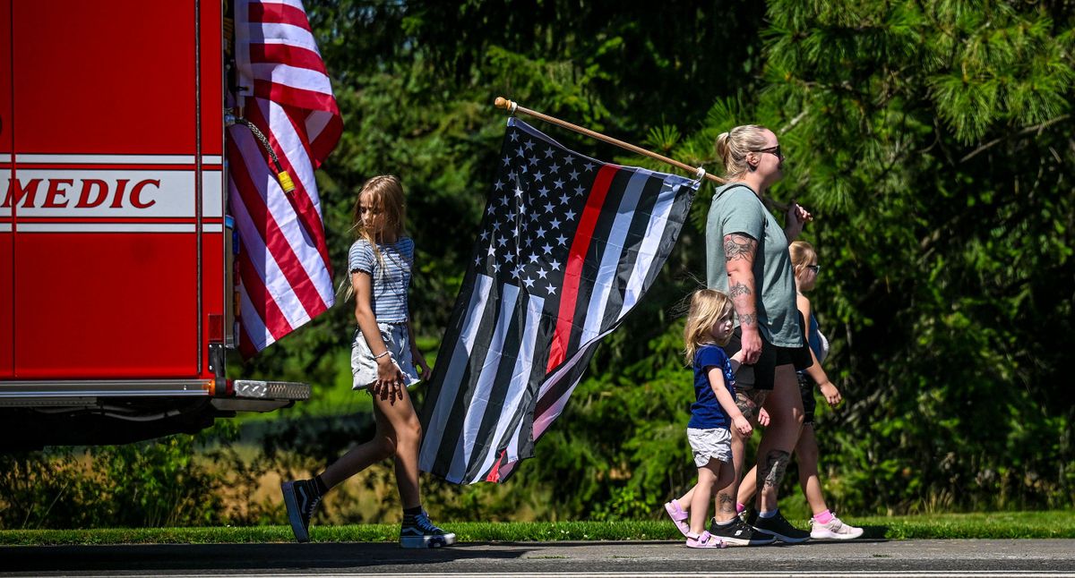 “Our community comes together,” says Erin Stemmermann as she walks with her children Katie, 2, Emily, 8, and Hailey, 9, during the funeral procession Friday for Kootenai Fire & Rescue Battalion Chief Frank Harwood in Coeur d’Alene. (Kathy Plonka/The Spokesman-Review)
