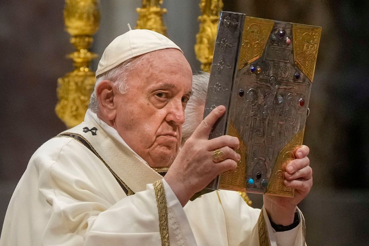 Pope Francis hoists the Gospel book Thursday during a Chrism Mass inside St. Peter’s Basilica at the Vatican.  (Gregorio Borgia)