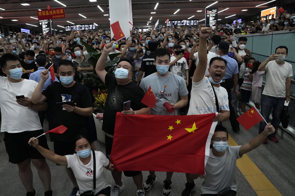 Residents holdings flags and chanting cheer as they wait for the arrival back to China of Meng Wanzhou, an executive of Chinese tech giant Huawei who was held by Canada for more than two years at America's request, at the airport in Shenzhen in southern China's Guangdong Province, on Sept. 25, 2021. Nine months into U.S. President Joe Biden's administration, there are signs of movement in what has been a fraught U.S.-China relationship.  (Ng Han Guan)