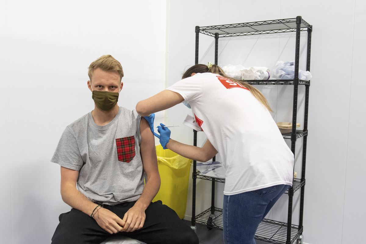 A man receives a dose of a COVID-19 vaccine, at a mass coronavirus vaccination centre held in Arsenal