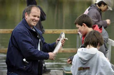 
Jim Dixon shows off the 16 1/2 -inch Eastern brook trout he landed to his sons Levi and Austin, back to the camera, on the dock Saturday morning at Fish Lake. 
 (Photos by Dan Pelle/ / The Spokesman-Review)