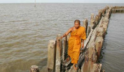 
Thai Buddhist monk Somnuk Attipanyo walks along a dam in August that he and others at Wat Khun Samut Chin community  have constructed to hold back the approaching sea. Associated Press
 (Associated Press / The Spokesman-Review)