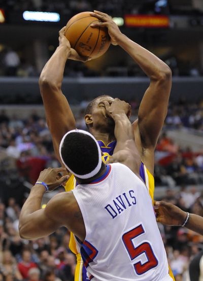 Lakers center Andrew Bynum gets a hand in his face by Clippers guard Baron Davis as he battles to the basket on Sunday. (Associated Press)