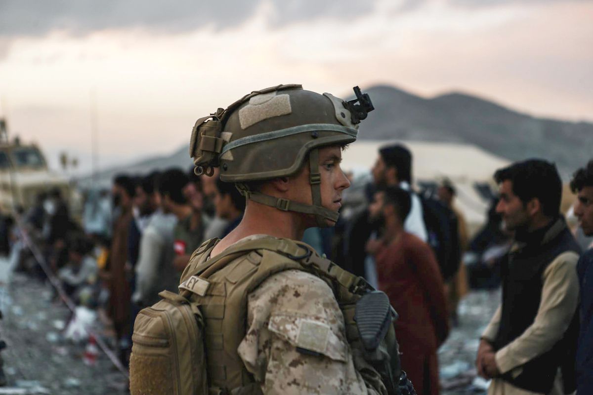 In this image provided by the U.S. Marines, a Marine assigned to Special Purpose Marine Air Ground Task Force-Crisis Response-Central Command assists evacuees during an evacuation at Hamid Karzai International Airport in Kabul, Afghanistan, Friday, Aug. 20, 2021.  (Sgt. Isaiah Campbell)
