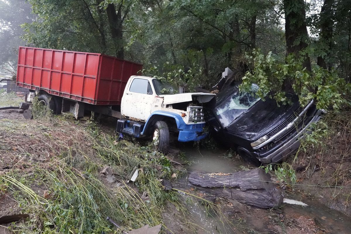A truck and a car sit in a creek Sunday, Aug. 22, 2021, after they were washed away the day before in McEwen, Tenn. Heavy rains caused flooding in Middle Tennessee and have resulted in multiple deaths as homes and rural roads were washed away.  (Mark Humphrey)