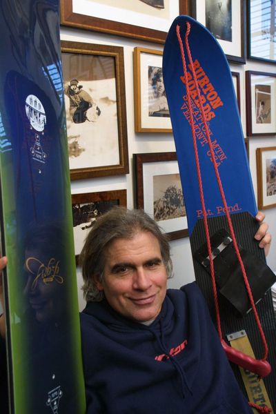 In this March 8, 2002 photo, Jake Burton Carpenter, owner of Burton Snowboards, shows an early model, right, and one of the newer snowboards, left, in his office in Burlington, Vt. (ALDEN PELLETT / associated press)