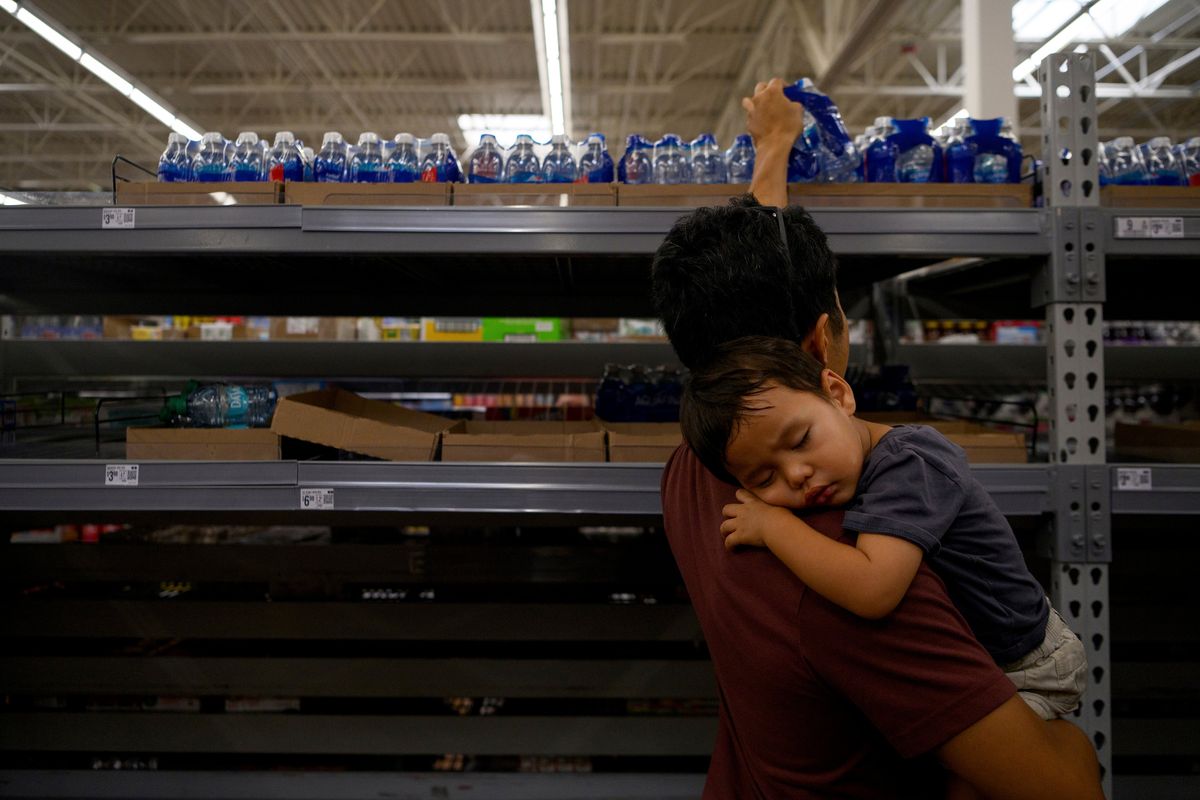 Roy Han, 41, holds his son Cedar, 2, as he grabs water from emptying shelves after evacuating from their home in Gulfport, Fla., to Orlando, Fla., on Tuesday, Oct. 8, 2024. Hundreds of thousands of people on Florida’s Gulf Coast clogged highways and drained gas pumps on Tuesday as they headed for higher ground, in an exodus that could be one of the largest evacuations in state history ahead of Hurricane Milton. (Callaghan O’Hare/The New York Times)  (CALLAGHAN O